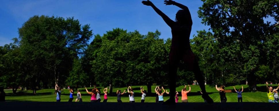 An instructor leads a zumba exercise session in a city park.