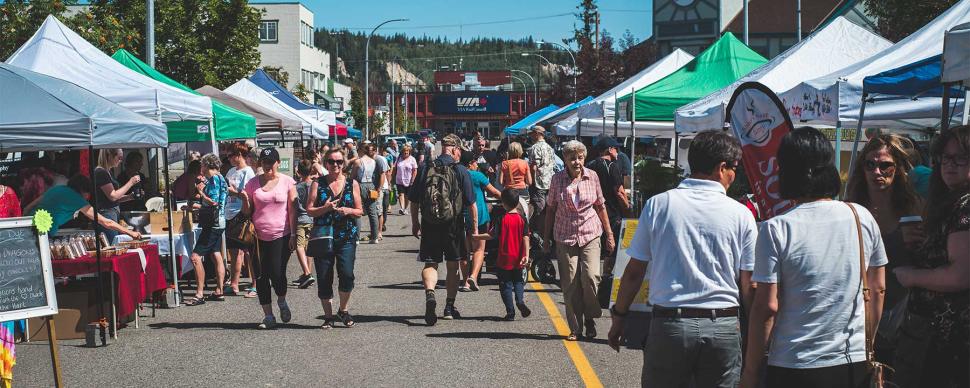People at a downtown farmer's market on a summer day.
