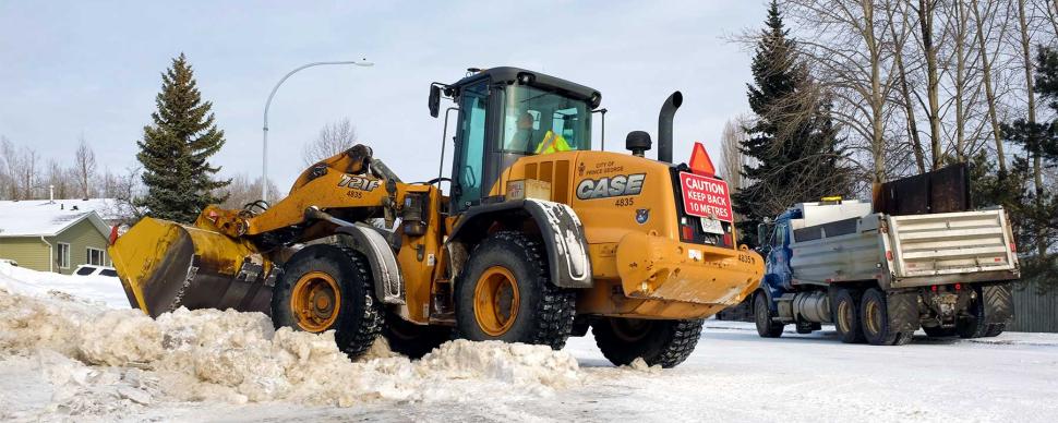 A snow plow clearing a residential street in winter.