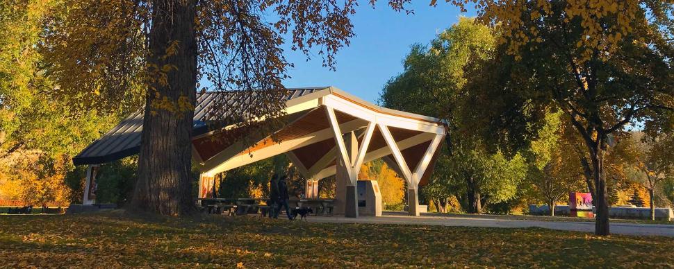 Two walkers waling by the pavilion at Lheidli T'enneh Memorial Park in the fall