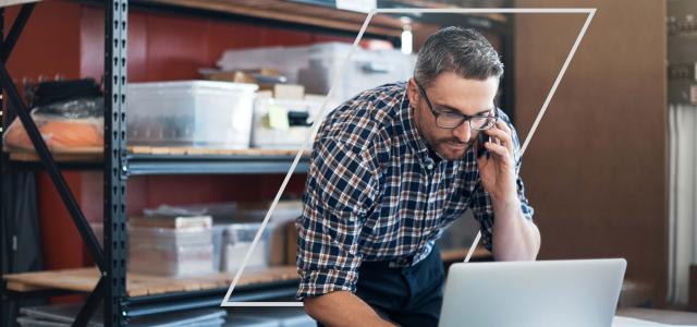 Businessman talking on smart phone using laptop at work