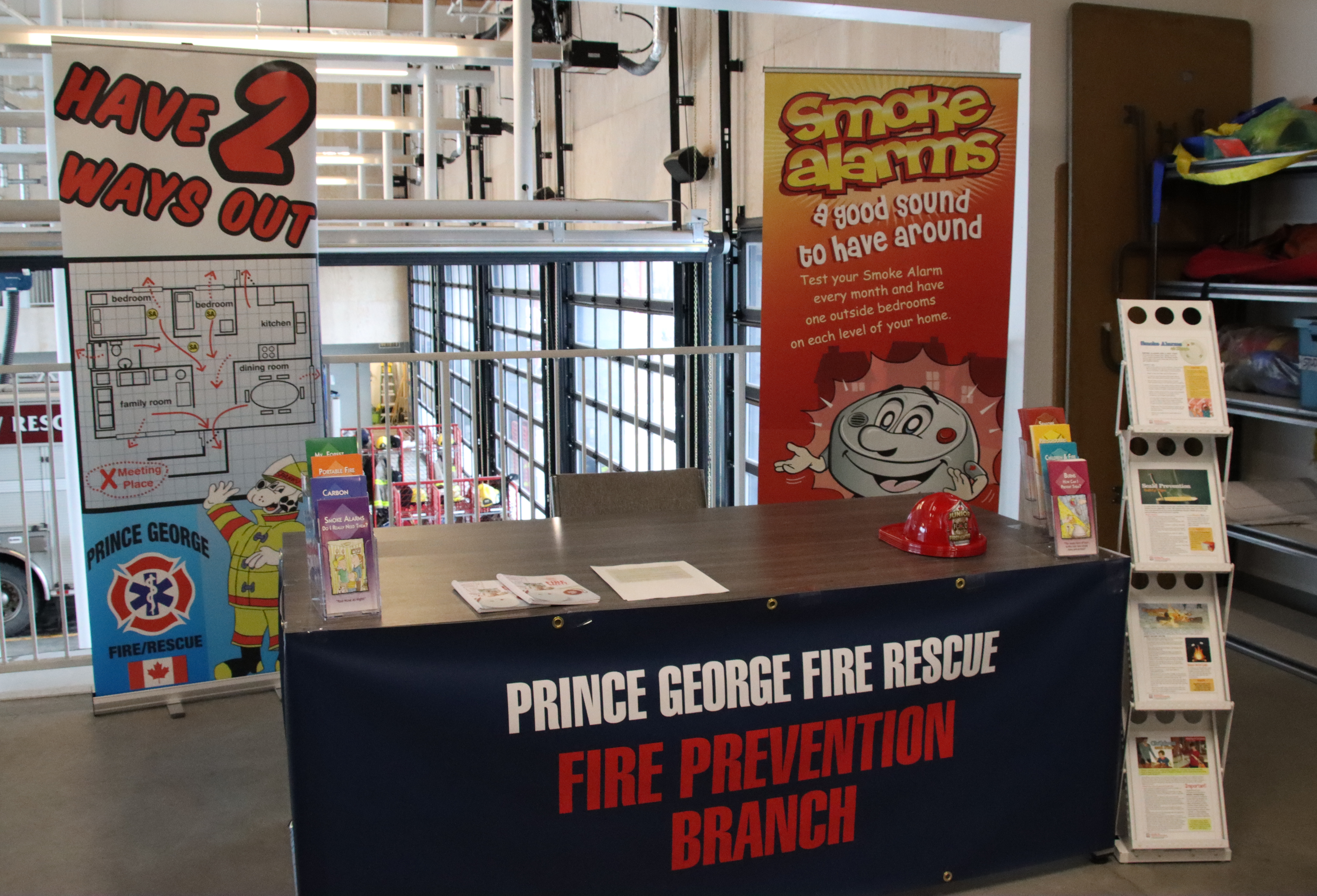 A table with banners and a rack of handouts. Tablecloth reads: Prince George Fire Rescue. Fire Prevention Branch.